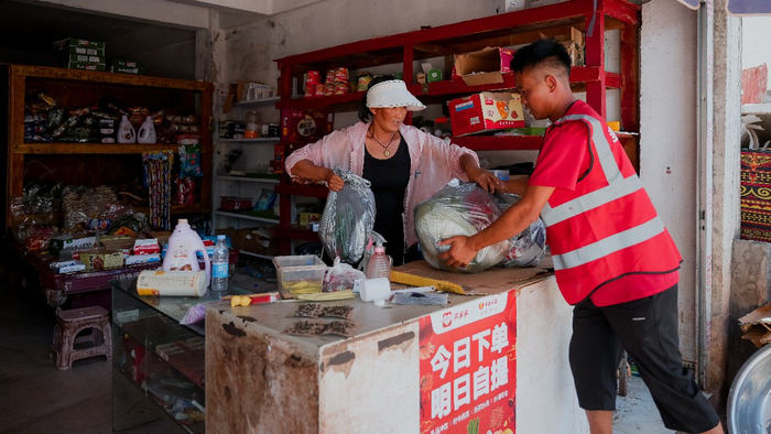 ▲吉克古千跑遍了美姑县的每一个乡镇，在合作团点张贴海报宣传。李靖|摄