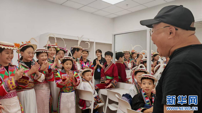 演出前，马为（右一）在后台为孩子们演唱《大海啊故乡》等歌曲。 新华网 刘丰 摄