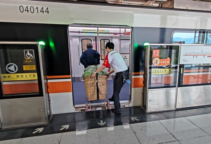 工作人員幫菜農將背簍運進(jìn)地鐵車(chē)廂。重慶軌道四號線(xiàn)建設運營(yíng)有限公司供圖