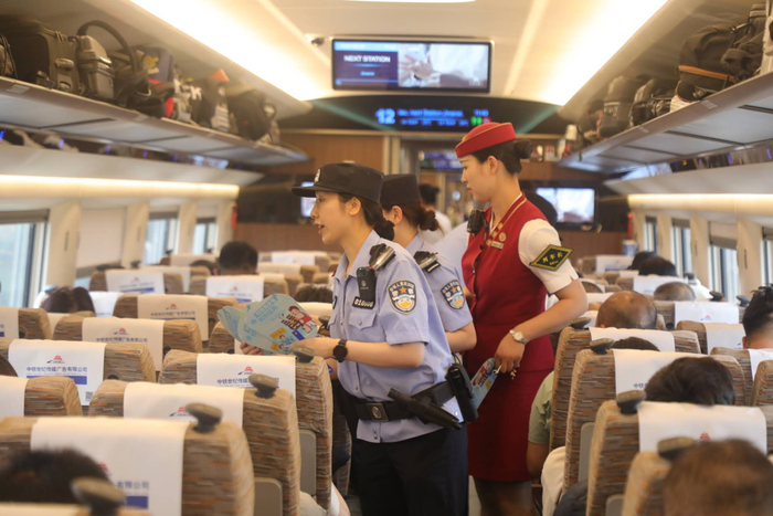 图为列车乘警协同列车长对车厢进行巡视并开展反诈宣传。