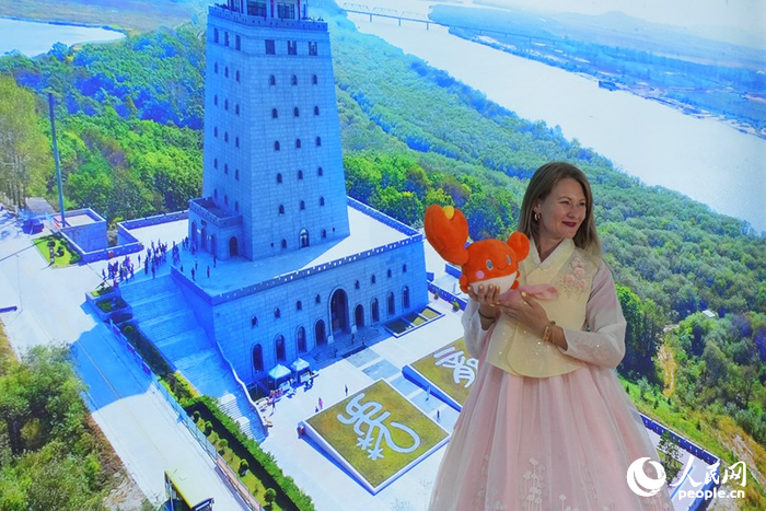 塔尼婭在延邊展館“一眼望三國”背景板前打卡拍照。人民網(wǎng)記者 李洋攝
