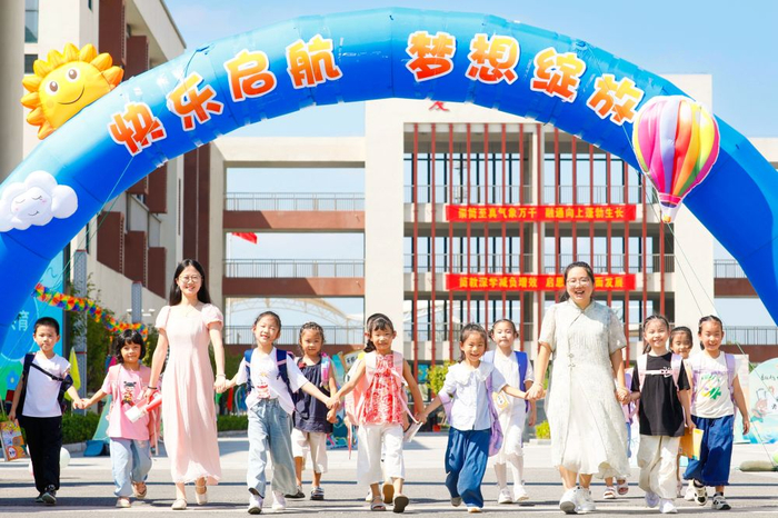 8月30日，在江苏省海安市南屏小学，一年级新生和老师一起走在校园里。新华社发（顾彬斌 摄）