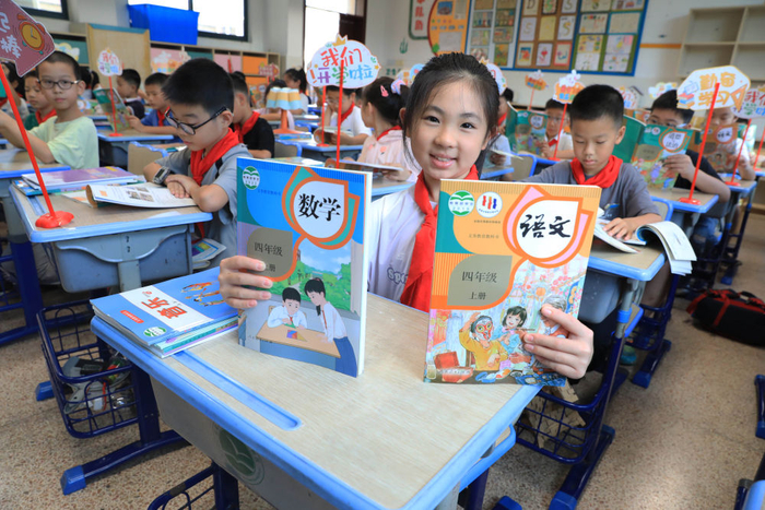 8月30日，在浙江省舟山市南海实验学校惠民桥小学校区，一名四年级的学生展示刚领到的新课本。新华社发（陈永建摄）