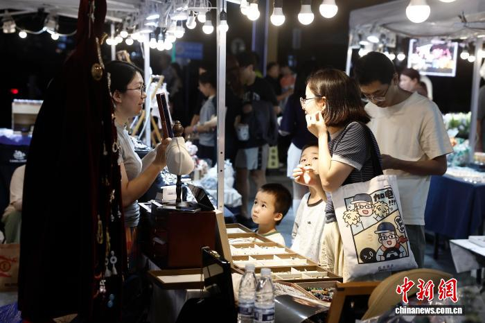 8月22日，市民在夜市选择耳环。近日，上海市召开推动夜间经济发展座谈会。　中新社记者 殷立勤 摄