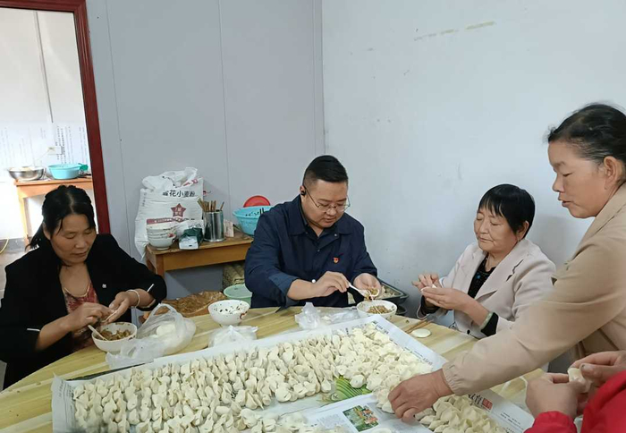 卢氏县民政局局长张家森（中）到徐家湾乡幸福村为老人包饭子。马飞摄