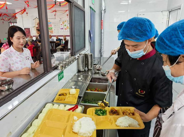 卢氏县莘城养老服务中心工作人员为老人打饭。张海军摄