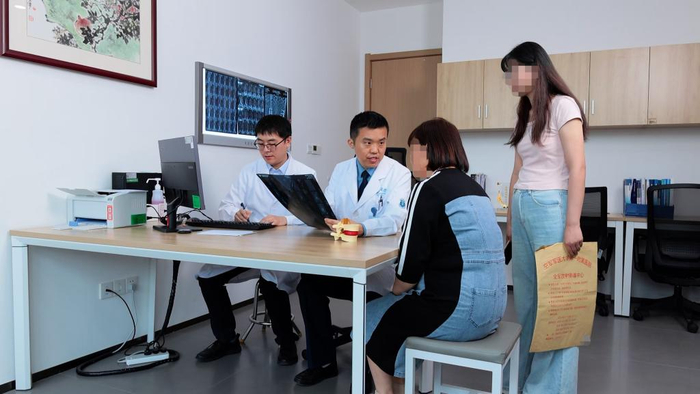 空军军医大学西京医院骨科主任黄景辉（左二）为患者解答脊柱侧弯问题。新华社发