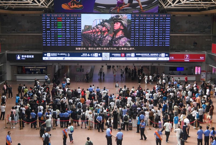 9月3日上午，北京西站大屏转播阅兵活动，众多旅客停下脚步观看。新京报记者 王贵彬 摄