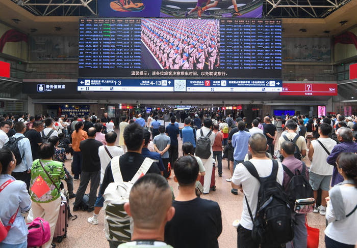 9月3日上午，北京西站大屏转播阅兵活动，众多旅客停下脚步观看。新京报记者 王贵彬 摄