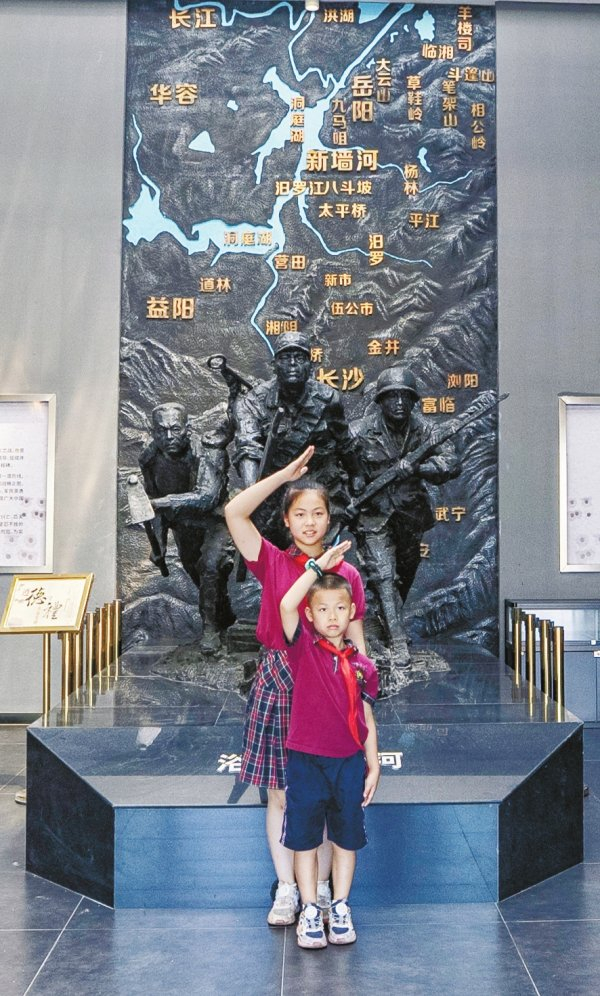 8月17日，两名学生在岳阳县博物馆新墙河抗战史实陈列展的《浴血新墙河》雕塑前敬礼。湖南日报全媒体记者 童臻熙 摄