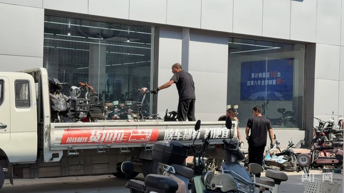 商家正搬運消費者以舊換新后的舊電動(dòng)自行車(chē)（央廣網(wǎng)記者 張晉鵬 攝）