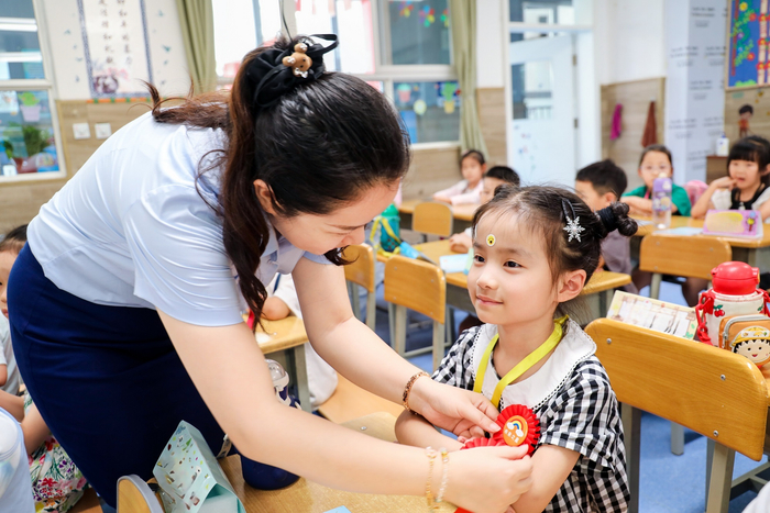 老师为新生带上奖励的“小勋章”（央广网发  西安高新第八小学供图）