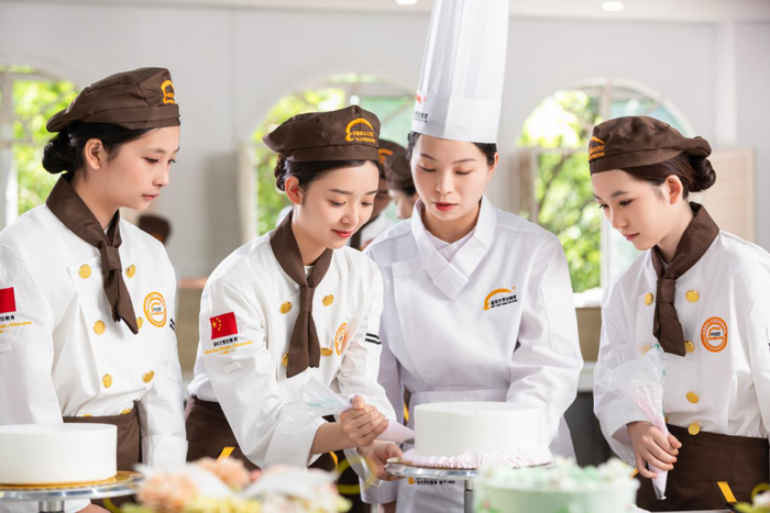 新东方烹饪学校的西点老师正悉心指导学生裱花技巧 图片来源：公司供图