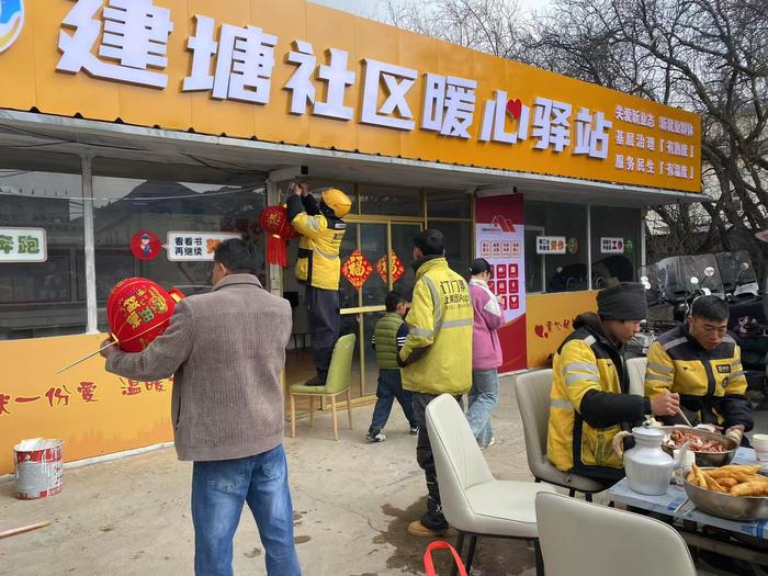 春节期间，当地组织在岗的外卖小哥在驿站贴春联、吃年夜饭