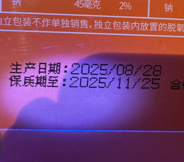 消费者用玉石探照灯照“南京冠生园 礼悦中秋”月饼礼盒外包装生产日期部分