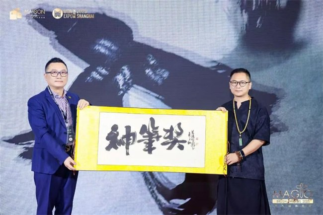 《神笔奖》书法题字卷轴授予仪式美陈网CEO、上海购物中心协会副会长谢赉先生（左）商业书法倡始人黄陵野鹤先生（右）