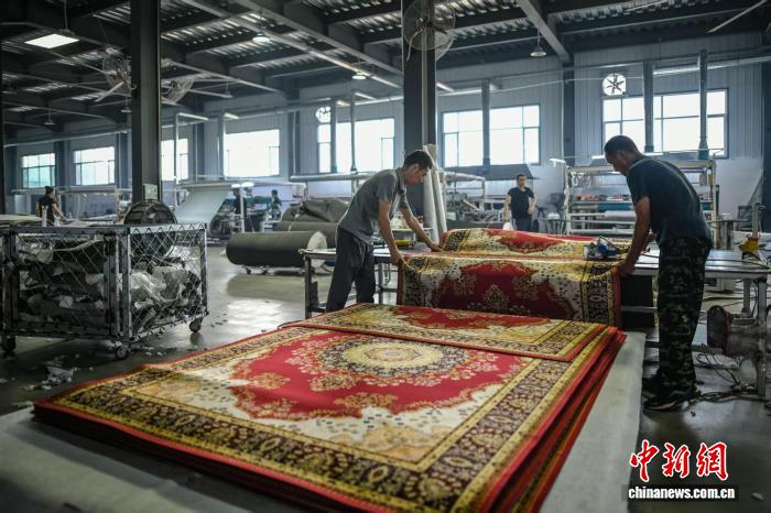 9月12日，天津市武清區崔黃口鎮一家地毯企業(yè)生產(chǎn)車(chē)間，工人對地毯進(jìn)行裁切。中新社記者 佟郁 攝