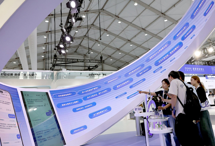 图为2025Inclusion·外滩大会上，工作人员（左）在向参观者介绍AQ健康医生的人工智能产品。记者　方喆　摄