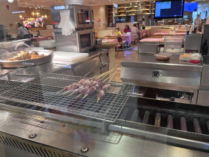 上游新聞?dòng)浾唿c(diǎn)的羊肉串，正在烤制。