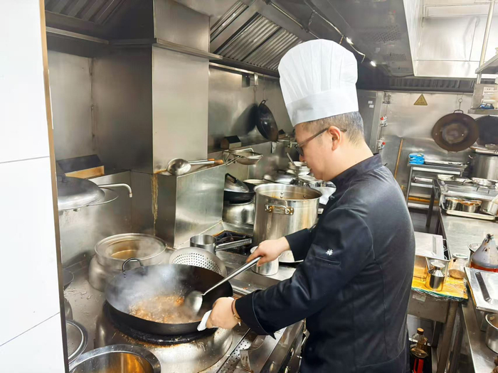 梅林正在烹饪，红烧菜“功夫考究”。劳动报记者陆燕婷 摄影