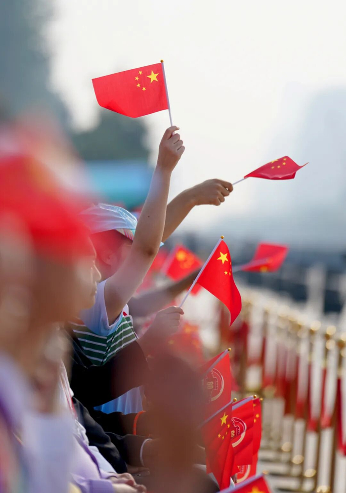 9月3日，纪念中国人民抗日战争暨世界反法西斯战争胜利80周年大会现场观众挥舞国旗。经济日报记者赵晶摄