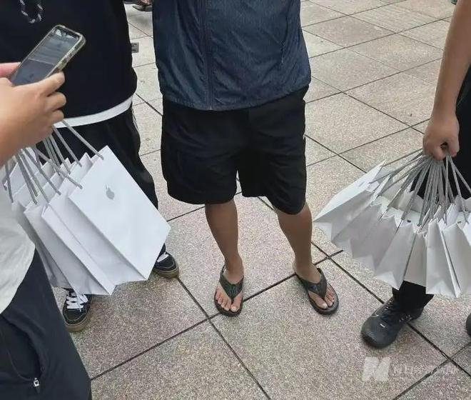直营店门外，“黄牛”手提数个苹果购物袋 图片来源：每经
