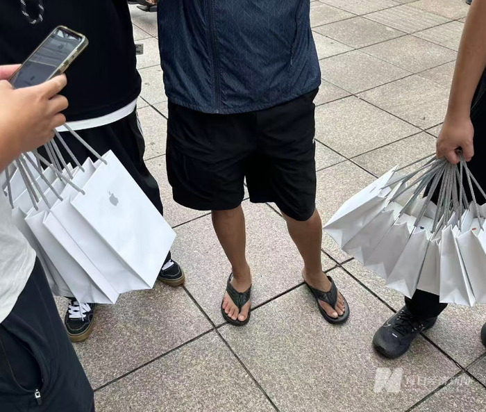 直营店门外，“黄牛”手提数个苹果购物袋 图片来源：每经记者 王晶 摄