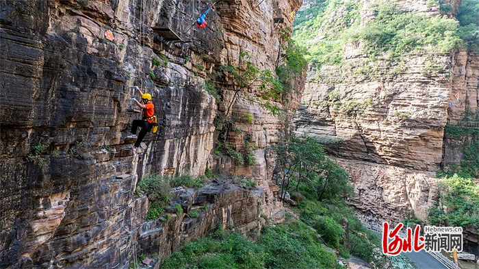 在邢台大峡谷景区，游客穿戴专业攀岩装备在体验飞拉达项目。图片来源：河北新闻网