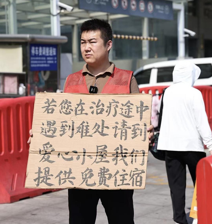 郑刚在齐鲁医院门诊楼前举牌吸引入住者