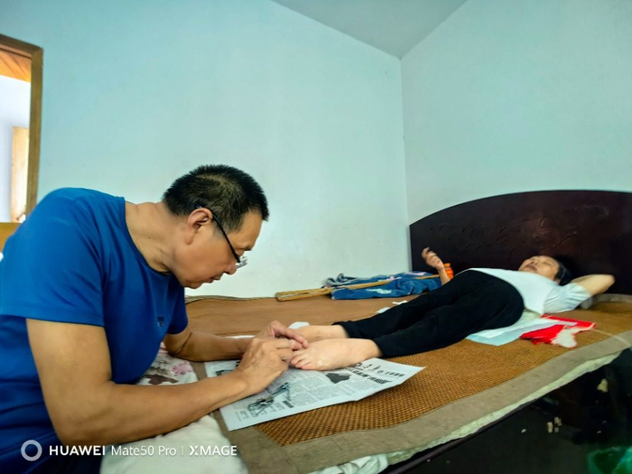 ▲馮以海正低頭為唐興芬修剪腳指甲。?記者???彭瑜??攝