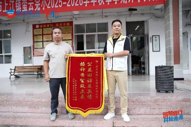 配图：上江镇中心学校党总支书记石佳辉向同方全球人寿志愿者代表颁发感谢锦旗