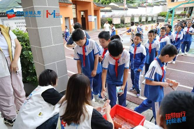 图为：志愿者为孩子们发放早餐