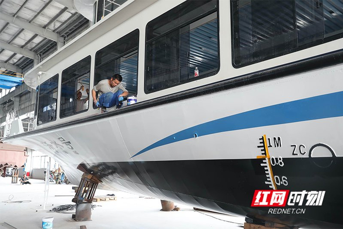 湖南萬駿船舶的生產(chǎn)區(qū)里，工人正在給船體刷漆。