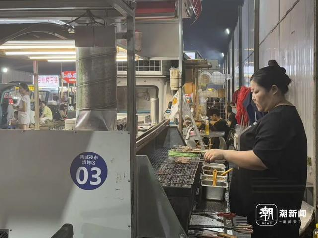 东北烧烤摊前，张静伟的妻子正在烧烤。戴佳轶/摄 