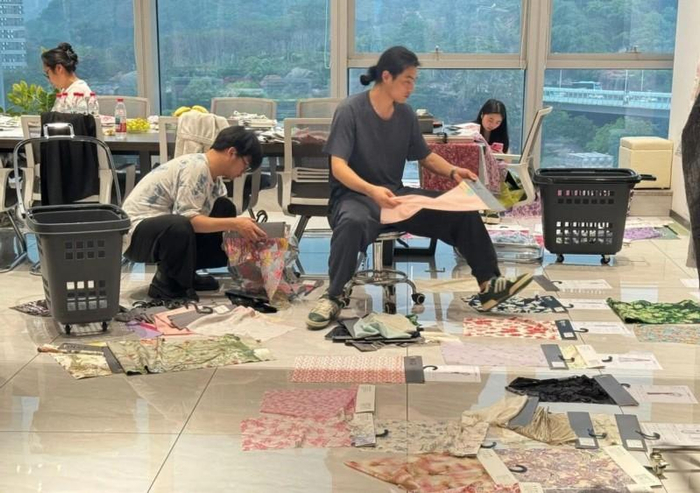 图为郝金龙与学生们在面料厂挑选面料