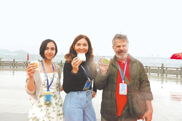 外国游客在三峡大坝前听中秋故事、品中秋月饼。（湖北日报全媒记者 邓云 摄）