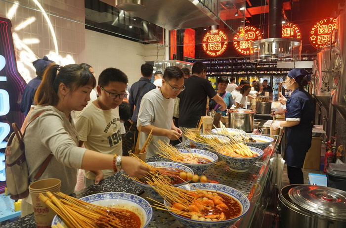 10月3日，游客在河北省唐山市唐山宴美食街品尝小吃。新华社发（梁志强 摄）