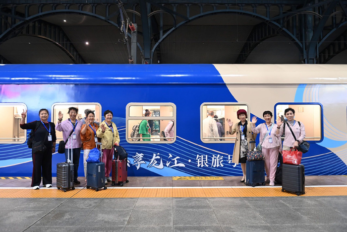 近日，在哈尔滨站，旅客在黑龙江今年开行的首趟“悠享龙江·银旅号”舒适型银发主题专列前合影。新华社发（原勇　摄）