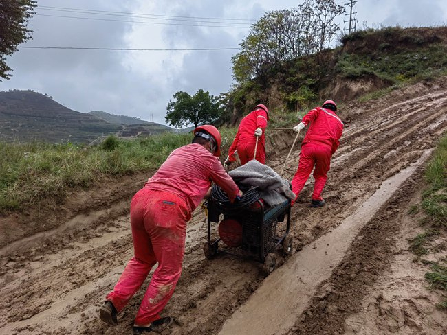 中国石油长庆油田采油十一厂桐川作业区通往镇53区块的陡峭山坡上，三位党员脚踩泥泞运输电机。