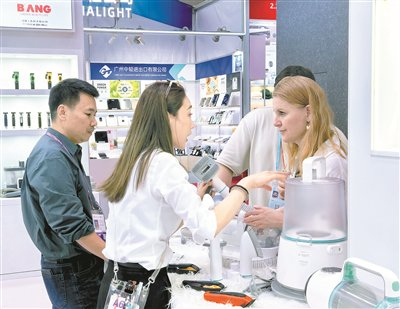 图为外籍采购商在展会现场咨询了解产品细节。 本报记者 薛鹏 摄