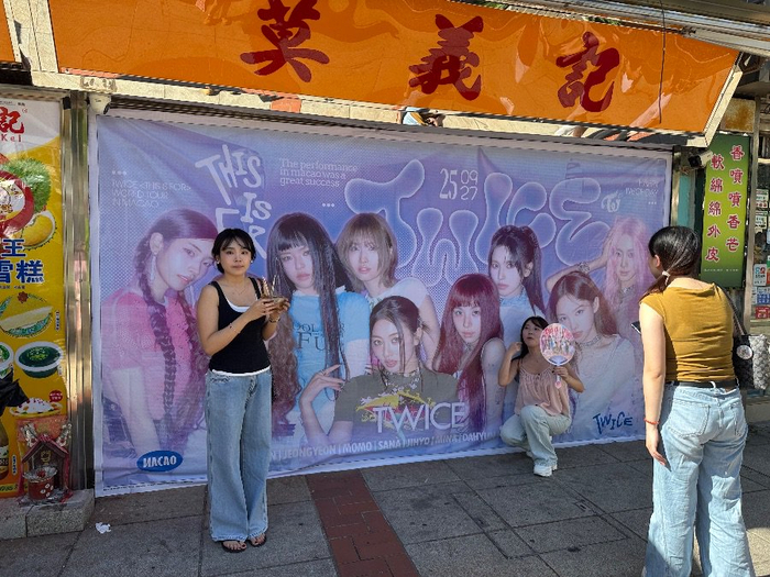 （粉丝在官也街商户张贴的应援海报前打卡留影。田静/摄）