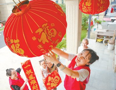浙江省湖州市长兴县吕山乡南杨新村，志愿者为新搬迁入住的村民家挂红灯笼。陈海伟摄（人民视觉）