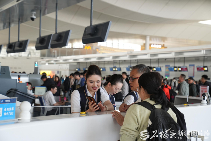 暑运期间，在乌鲁木齐天山国际机场，南航服务台工作人员在回答旅客问询。骆俊峰摄