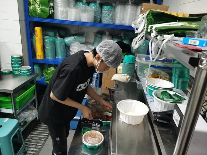  无堂食餐饮店的工作人员正在“做饭”——将标准化生产的“浇头”拆包淋到饭上。 陈玺撼摄