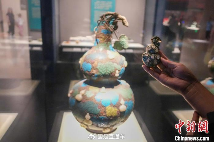   资料图：游客手持“珐琅镶玉葫芦”文创产品与河南博物院馆藏文物对比。中新社记者 范晓恒 摄