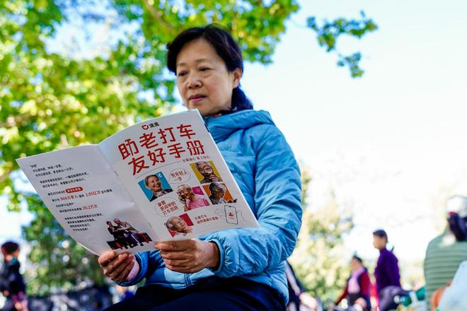 图为：严阿姨正在阅读助老打车友好手册