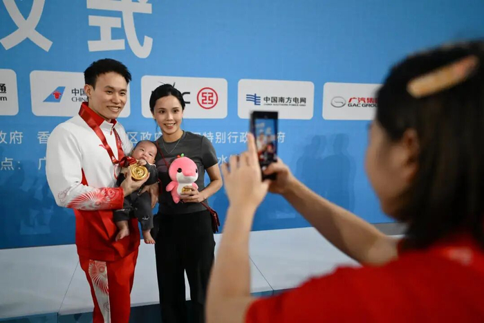 全红婵变身摄影师为谢思埸和妻儿拍照。图片来源：羊城晚报