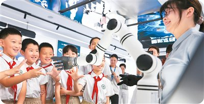 9月26日，在江苏省无锡市梁溪区脑机科学创新示范中心，学生与脑控机械臂做互动游戏。胡攀学摄（人民图片）