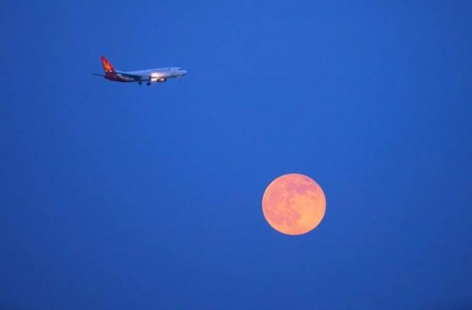 2025年10月11日，浙江省温州市，飞机与满月同框。新华社图片