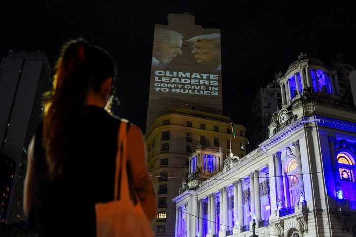  当地时间2025年11月5日，巴西里约热内卢，COP30召开前夕，气候活动人士在一栋建筑上投射包含巴西总统卢拉和美国总统特朗普肖像的标语，引发路人驻足观看。 IC Photo